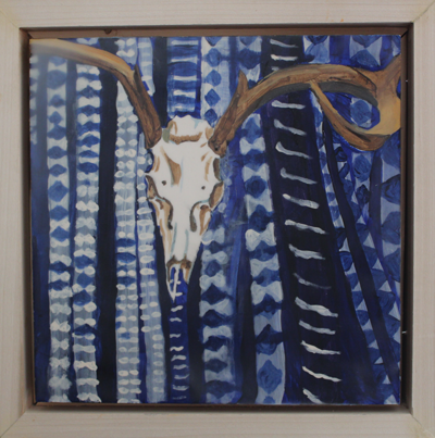A deer skull is hung on the wall in front of blue looking fabric with white patterns on the fabric