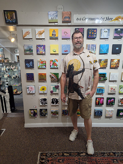 Man standing in front of multiple small pieces of painted artwork