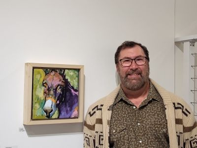 Artist standing next to painting of donkey